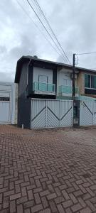 a house with a white fence and a building at Casa de praia in Praia Grande