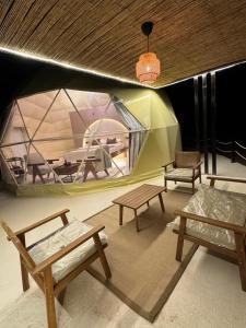 Al RakaにあるSunset domes private campのテント内のベンチとテーブル付きの部屋