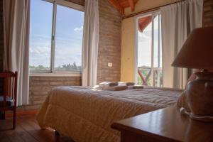 a bedroom with a bed and a large window at Complejo de cabañas- Lomas del Sol in Los Reartes