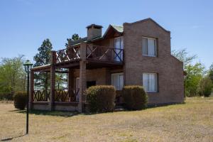 a brick house with a balcony on top of it at Complejo de cabañas- Lomas del Sol in Los Reartes
