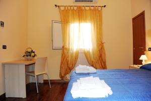 1 dormitorio con cama azul, escritorio y ventana en L'Antica Dimora, en San Pietro Vernotico