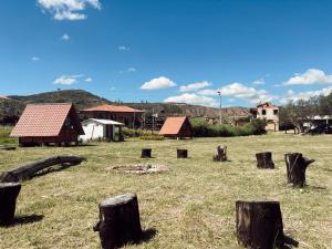 a group of logs in a field next to some buildings at Camping Bugambil in Sáchica