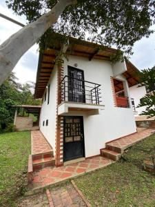 a white house with a porch and a balcony at Cabaña Campestre - Puente Nacional in Puente Nacional