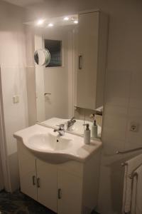 W białej łazience znajduje się umywalka i lustro. w obiekcie Apartments Constance w Konstancji