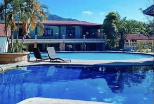 a swimming pool with two chairs and a house at La Vista Pansol Resort Complex by RedDoorz in Pansol