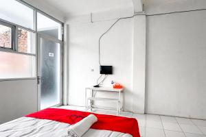 a bedroom with a bed and a desk with a television at RedDoorz Syariah at Neu Hostel Cisarua Lembang in Lembang +21 photos
