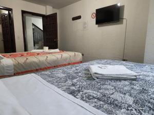 a room with two beds and a flat screen tv at Hostal María - Otavalo in Otavalo
