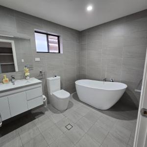 a bathroom with a tub and a toilet and a sink at New 5x bedroom The Ponds House in Schofields