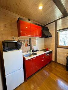 a kitchen with red cabinets and a white refrigerator at Second House ホッポッタ in Kita-karuizawa
