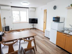 a living room with a table and a kitchen at section-inn in Chitose