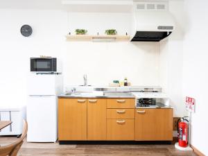 a kitchen with wooden cabinets and a white refrigerator at section-inn in Chitose