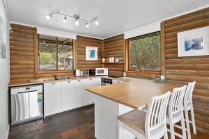 a kitchen with white cabinets and wooden walls at The Log Cabin - 2 Scenic View Drive, Second Valley in Second Valley