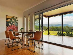a dining room with a table and chairs and a balcony at 4 bedroom Cottage with swimming pool in Cooranbong