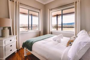 a bedroom with a bed and two windows at 4 bedroom Cottage with swimming pool in Cooranbong +73 photos