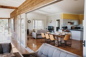 a living room and kitchen with a table and chairs at 4 bedroom Cottage with swimming pool in Cooranbong