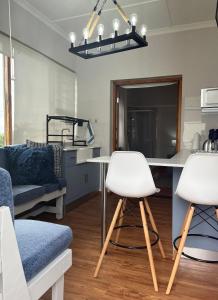 una cucina e un soggiorno con 2 sgabelli bianchi di Casa Sí Apartment a Gqeberha