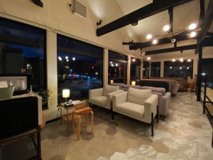 a living room with couches and tables and windows at KIIIYA cafe&hostel in Azumino