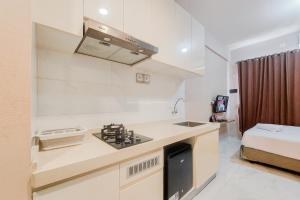 a kitchen with a sink and a stove in a room at Good Designed and Restful Studio Sky House BSD Apartment By Travelio in Tangerang