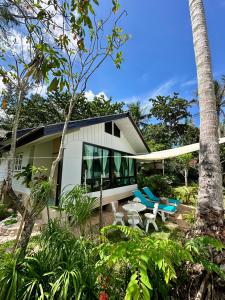 a white house with a table and chairs and trees at 2BD beachfront house in Chaloclum in Mae Haad
