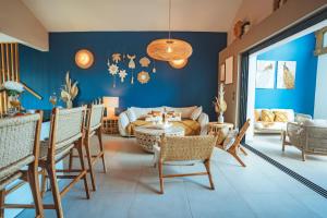 a living room with blue walls and a table and chairs at Villa Bo'M Bleue in Petite Île