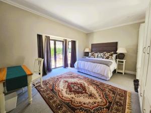 ein Schlafzimmer mit einem Bett, einem Tisch und einem Schreibtisch in der Unterkunft 2 Annie's Place Rawdons Country Estate in Nottingham Road