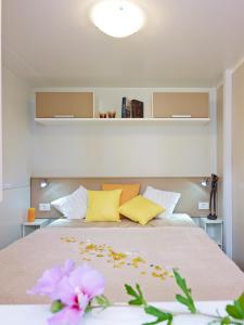 Mobile Homes Adria Ankaran في أنكاران: غرفة نوم بسرير كبير ومخدات صفراء وبيضاء
