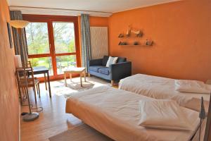 a bedroom with two beds and a couch and a chair at EcoHotel L’Aubier in Montézillon