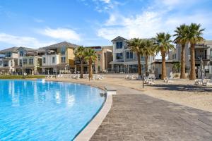 a swimming pool with palm trees and houses at Lagoon Vibes townhouse in St. George