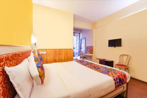 une chambre avec un lit et une télévision au mur dans l'établissement FabHotel JS Heritage, à Kodaikānāl