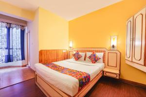 une chambre avec un grand lit aux murs jaunes dans l'établissement FabHotel JS Heritage, à Kodaikānāl