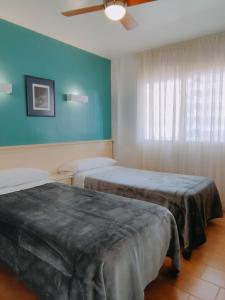 a room with two beds and a ceiling fan at Apartamentos Eldorado in Lloret de Mar