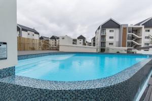 a large swimming pool in front of some apartment buildings at Just Beachy Bellamare Apartment in Summerstrand