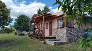a small house with a stone wall at Cabañas Mónika IV Sur in Huerta Grande
