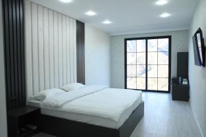 a bedroom with a white bed and a window at Grand Hotel Kapan, Armenia in Kapan