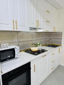 a white kitchen with white cabinets and a microwave at Sumqayit citi in Sumqayıt