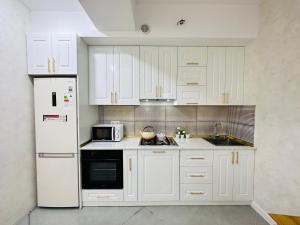 a kitchen with white cabinets and a white refrigerator at Sumqayit citi in Sumqayıt