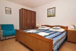 a bedroom with a bed and a blue chair at Apartments Zlatica in Šilo