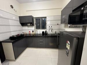 a kitchen with black cabinets and a stainless steel refrigerator at Trinetra Homes 61 in Bangalore