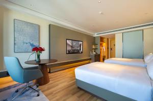 una camera d'albergo con un letto e una scrivania di 青岛西海岸城市阳台Madison酒店 a Qingdao Altre 7 foto