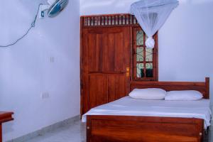 a bedroom with a wooden bed with a wooden door at Tourist Holiday Inn in Dambulla