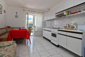 a kitchen with white cabinets and a table with a red table cloth at Apartments Zlatica in Šilo