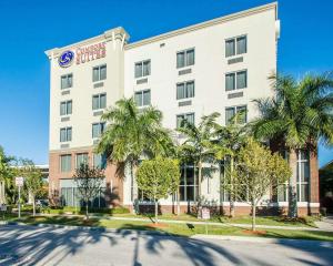 a hotel with palm trees in front of a building at Comfort Suites Miami Airport North in Miami