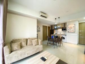 a living room and kitchen with a couch and a table at Cozy and Minimalist 2BR at 8th Floor The Oasis Cikarang Apartment By Travelio in Cikarang