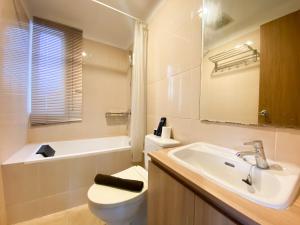 a bathroom with a sink and a toilet and a tub at Cozy and Minimalist 2BR at 8th Floor The Oasis Cikarang Apartment By Travelio in Cikarang +16 photos