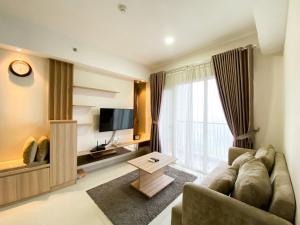 a living room with a couch and a television at Cozy and Minimalist 2BR at 8th Floor The Oasis Cikarang Apartment By Travelio in Cikarang