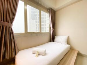 a small bed in a room with a window at Cozy and Minimalist 2BR at 8th Floor The Oasis Cikarang Apartment By Travelio in Cikarang