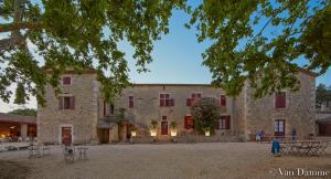 a large stone building with tables and chairs in front of it at Gîtes du Domaine des Dames in Vallon-Pont-dʼArc