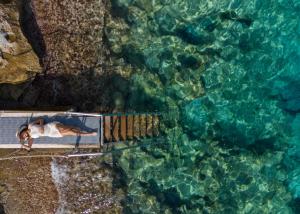 a man laying on a walkway next to the water at Leonardo Crystal Cove Hotel & Spa – Adults only in Protaras