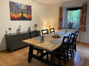 a dining room table with chairs and a painting on the wall at Le Cat'saisons in Wellin