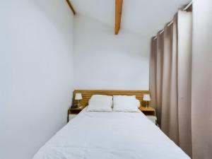 a bedroom with a bed with white sheets and two lamps at Saint-Hilaire - 350m de la plage in Plage-des-Demoiselles